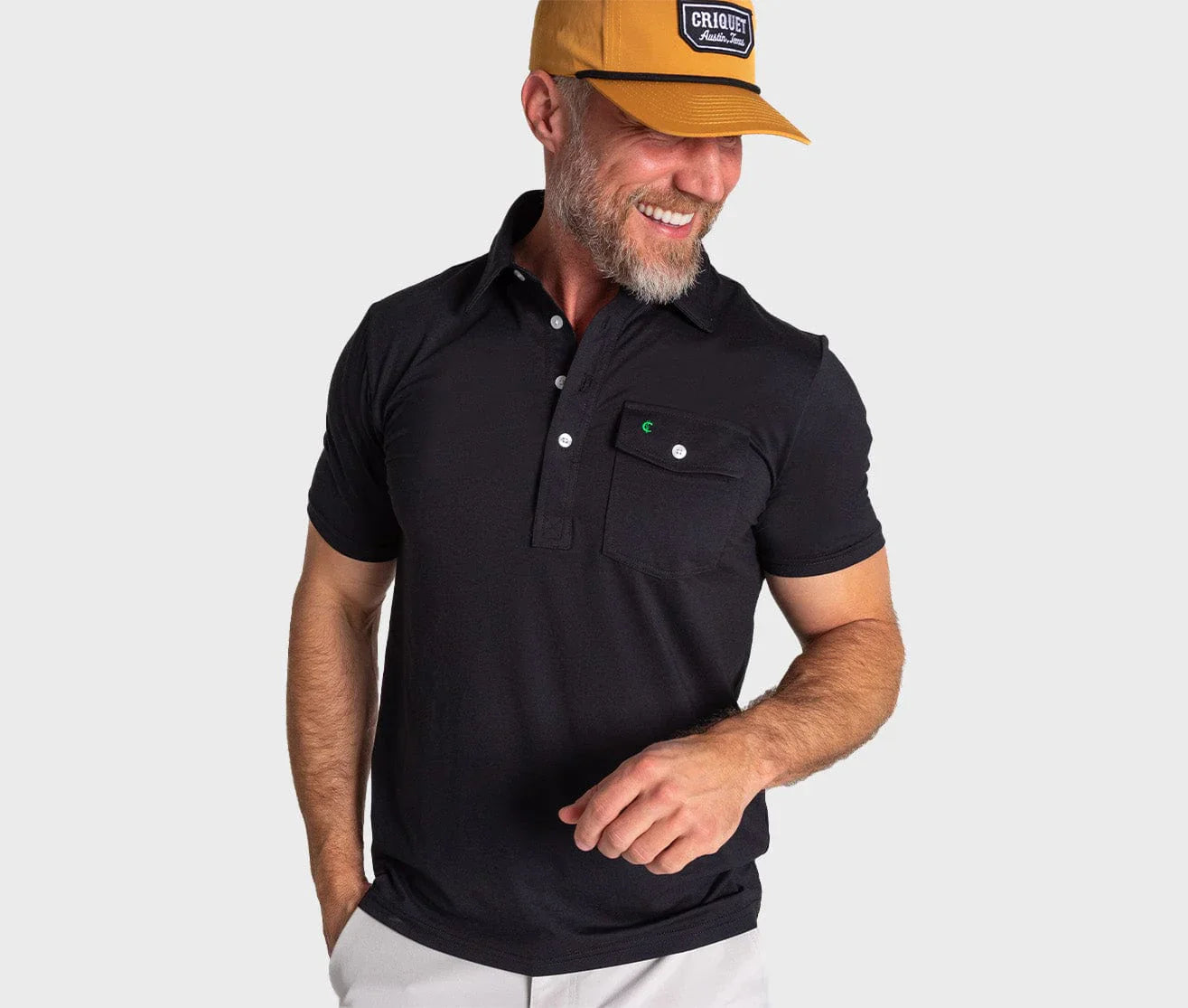 Black Criquet Performance Players Shirt with moisture-wicking fabric, modeled by a man wearing a yellow cap.
